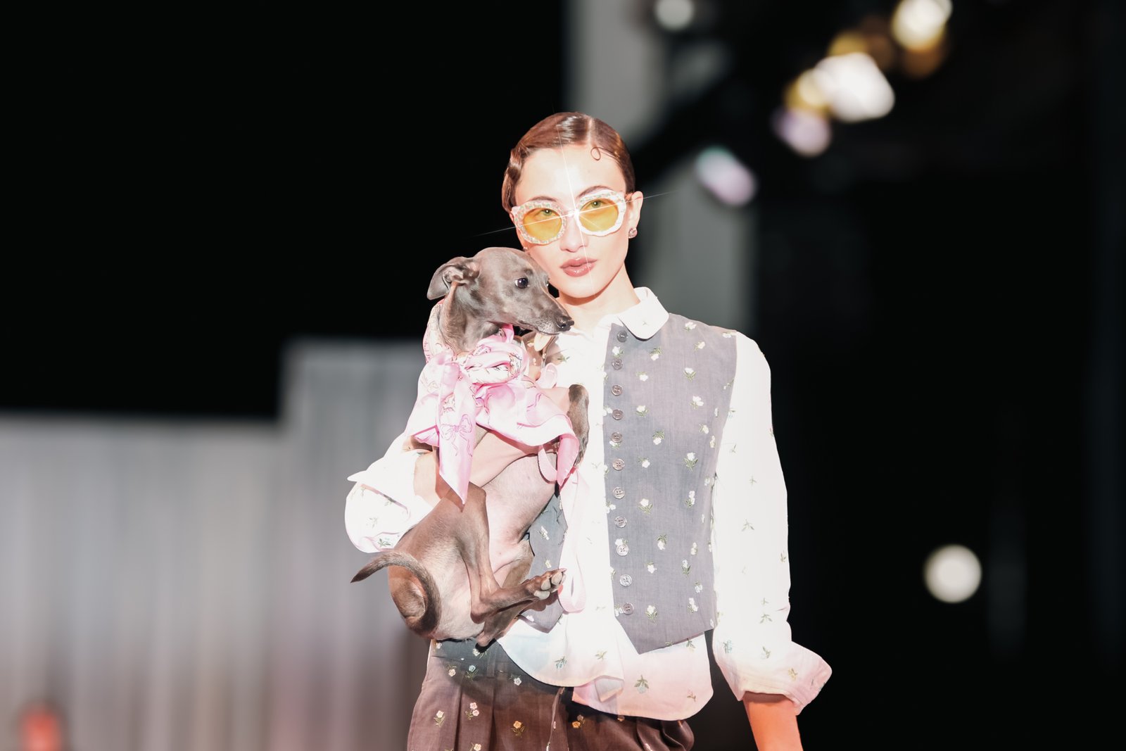 Modelo en pasarela sosteniendo un perro pequeño